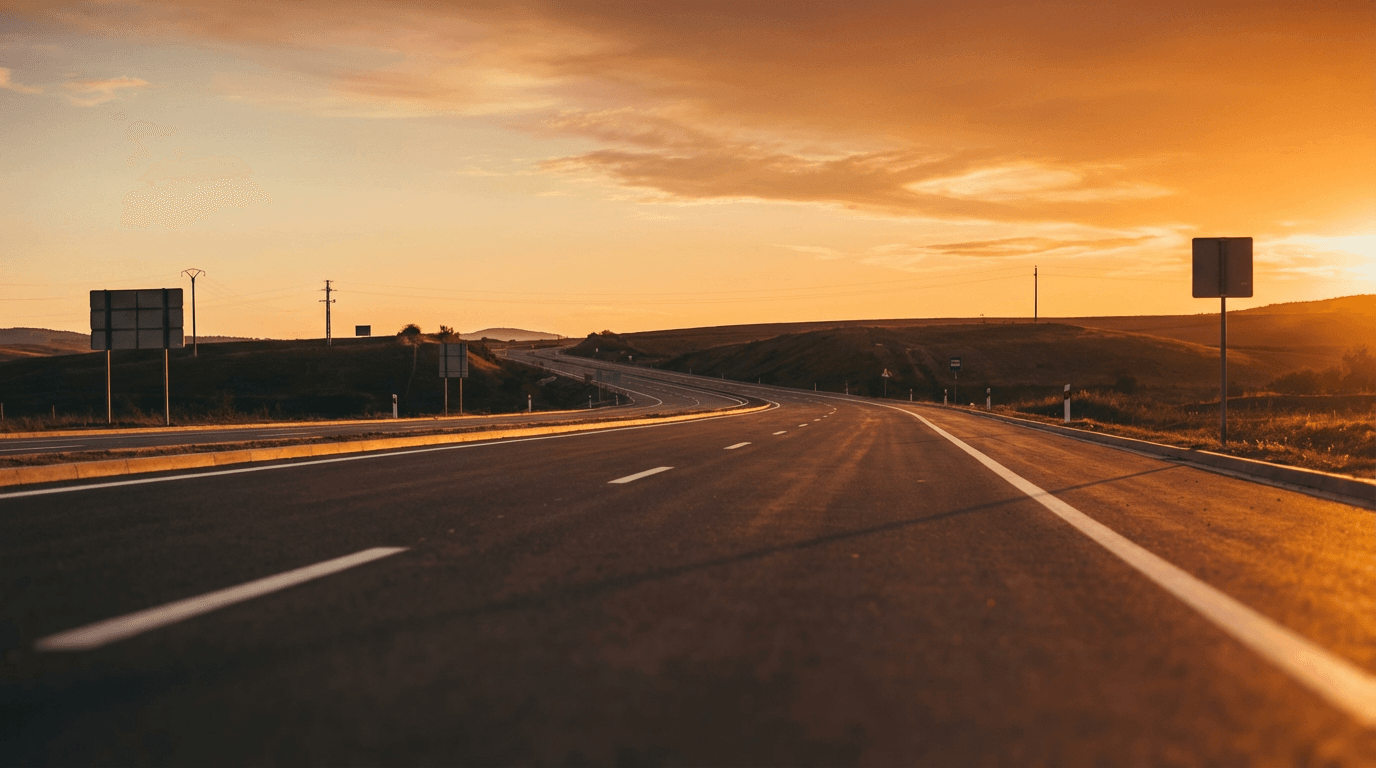 Open highway leading toward a sunrise with a truck in the distance